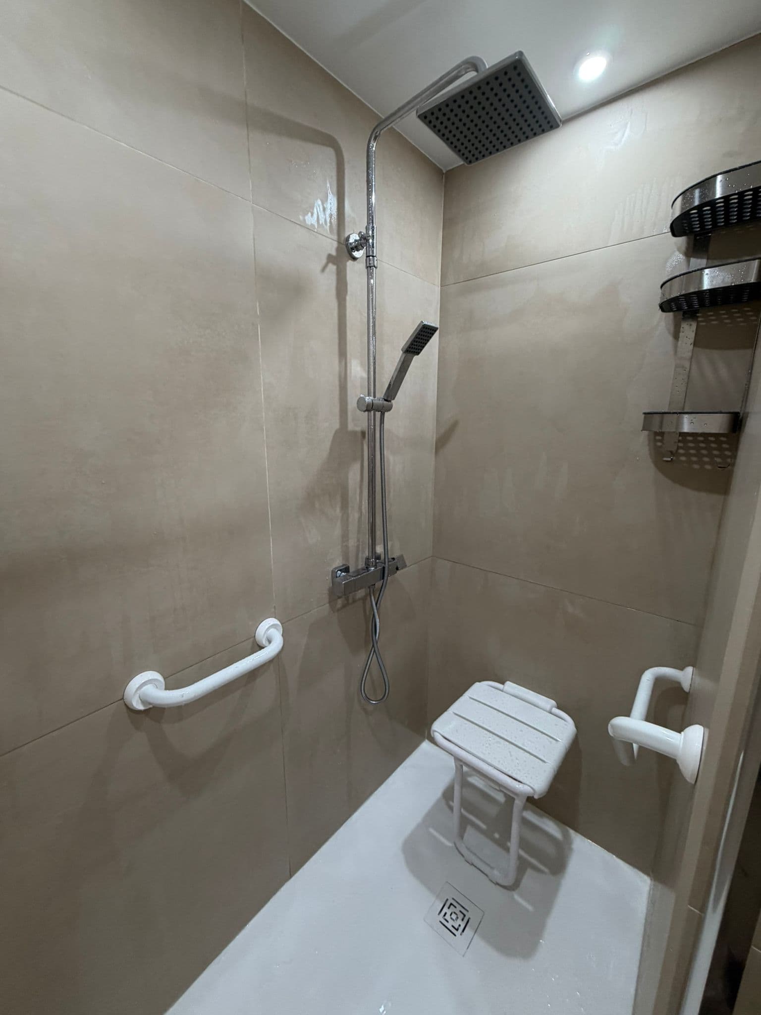 Détail douche accessible avec barres d'appui et siège